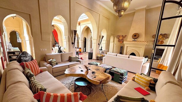A spacious living room with a high ceiling, arched doorways, and a fireplace.