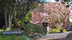 A brick house with a front door, surrounded by flowering trees and a sign reading "Little Barham". - Little Barham B&B (Braintree)