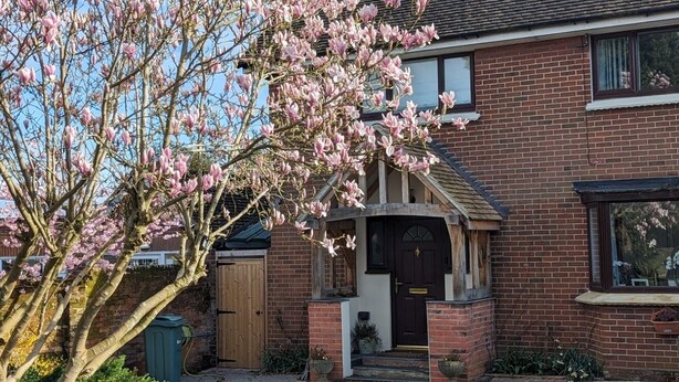 A two-story brick house with a front porch, a wooden door, and a small garden area. - Little Barham B&B (Braintree)