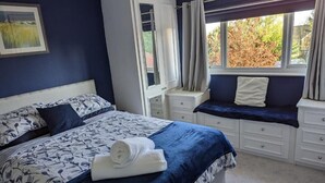 A bedroom with a bed, a window seat, and a nightstand. - Little Barham B&B (Braintree)