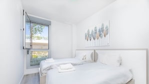 Een moderne slaapkamer met twee bedden, een groot raam en een kunstwerk aan de muur.