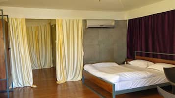 A bedroom with a bed, a ceiling fan, an air conditioning unit, and curtains.