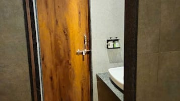 A modern bathroom with a wooden door, a sink, and a small rug on the floor.