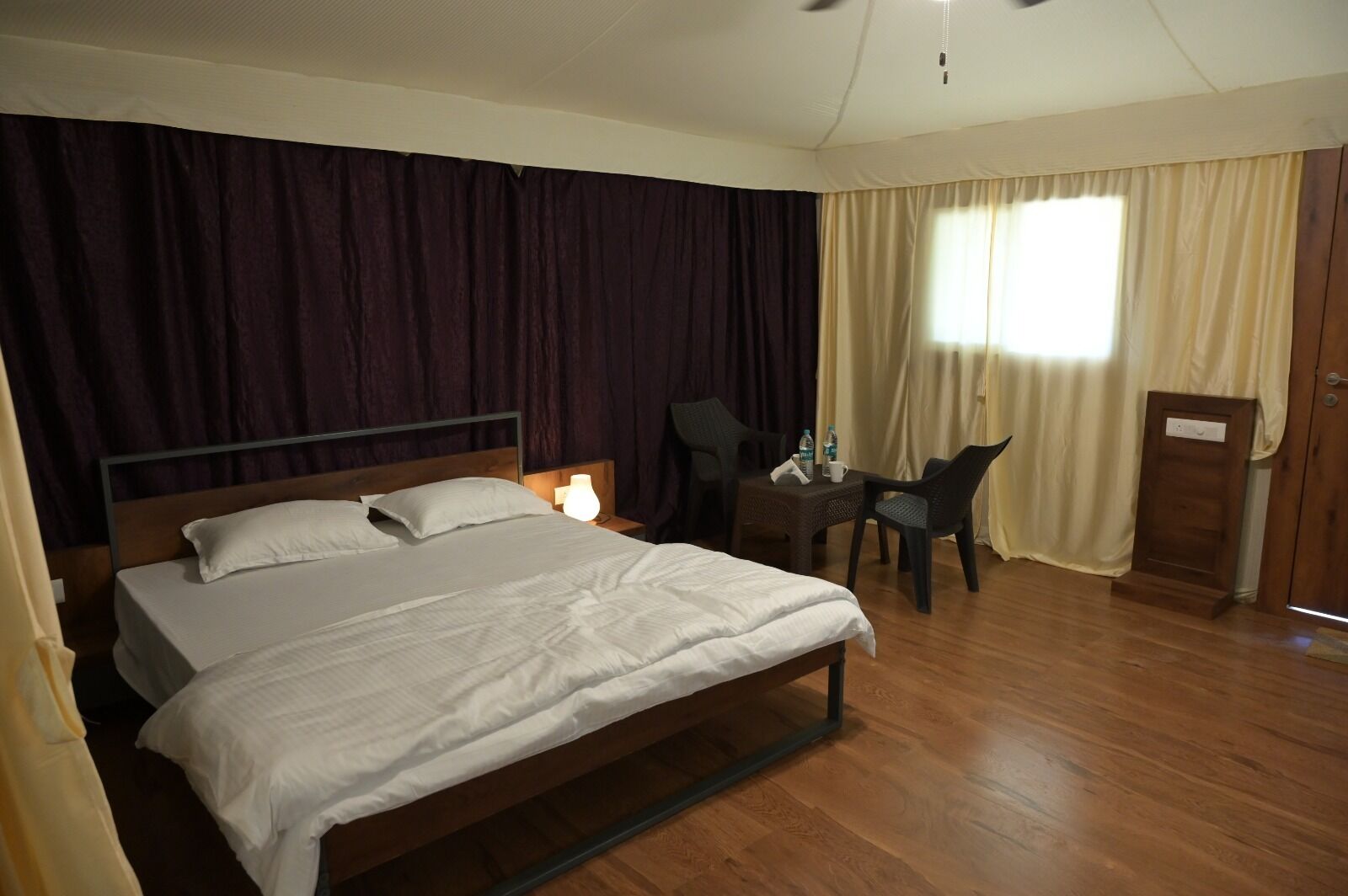 A hotel room with a large bed, a desk with a chair, and a wardrobe.
