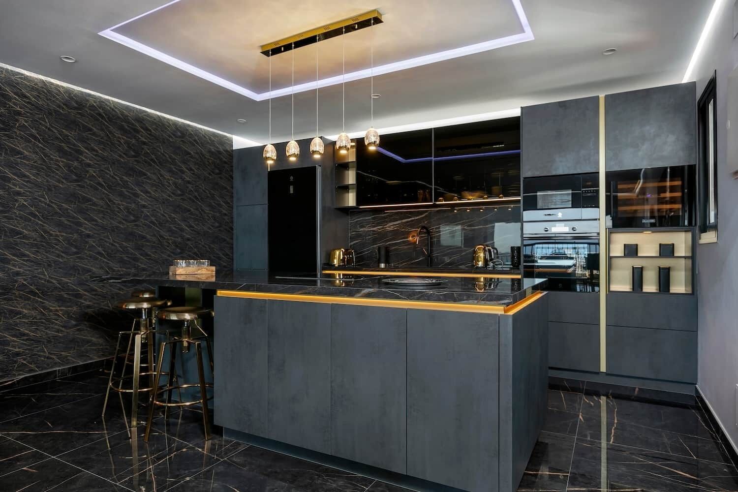 Cozinha moderna com ilha central, painel de mármore escuro e luminárias contemporâneas.