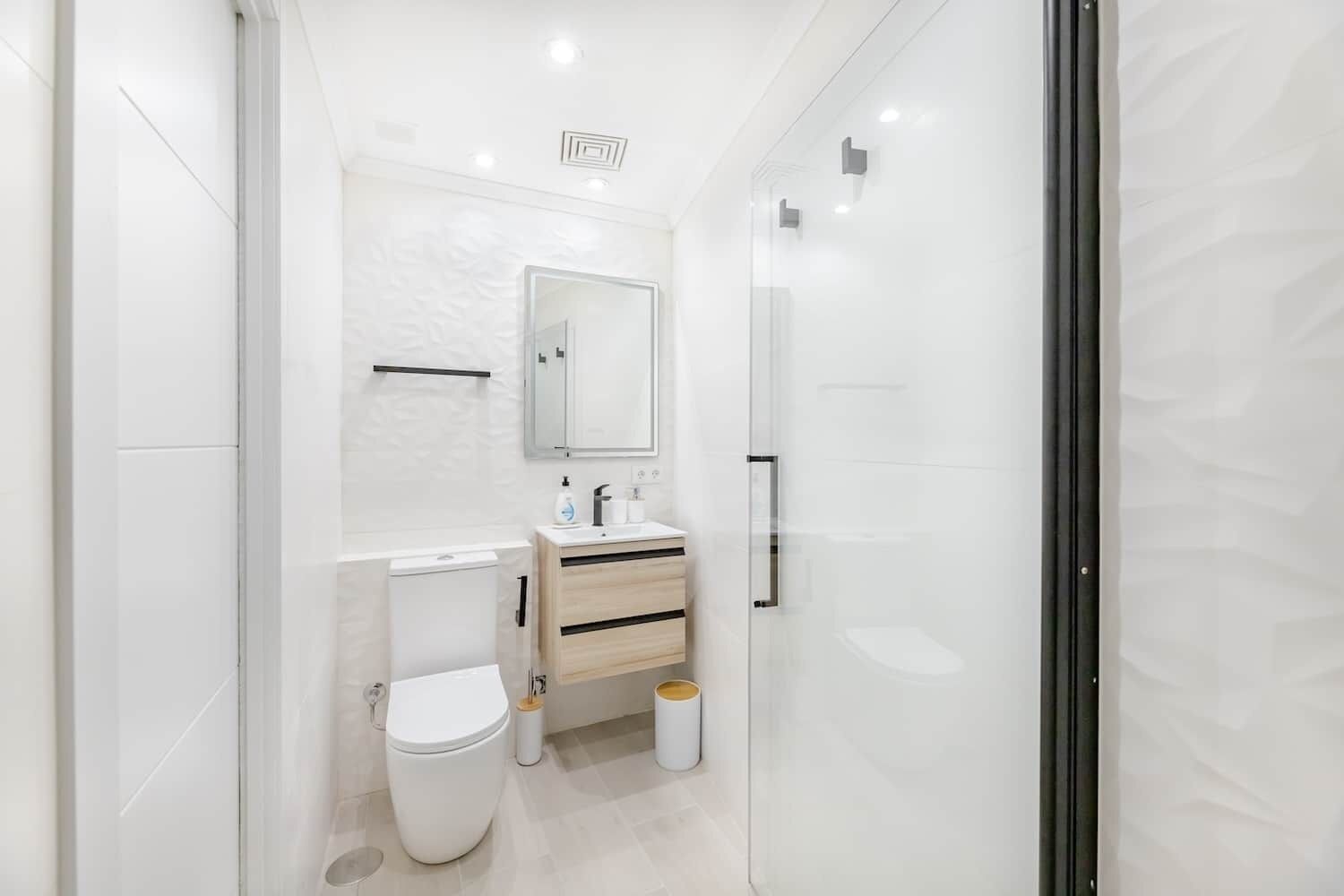 Ein modernes Badezimmer mit Toilette, Waschbecken und Spiegel.