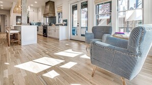 Un'ampia cucina con un'isola grande, pavimento in legno e vista sull'esterno tramite ampie finestre.