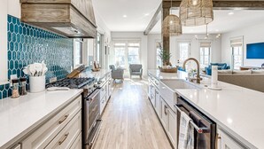 Una cucina moderna con isola centrale, mobili in legno e una parete rivestita con piastrelle blu.