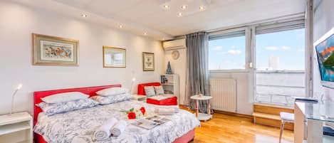 Une chambre moderne avec un grand lit, un bureau, une chaise et une fenêtre donnant sur la ville.