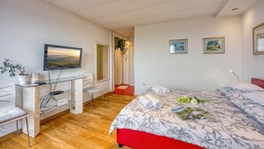 A hotel room with a bed, a desk, a chair, a television, and artwork on the walls. - Cozy penthouse with Panoramic view (Zagreb)