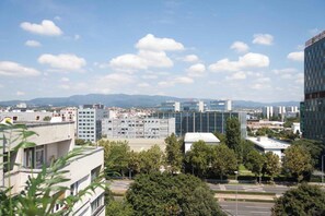 A cityscape with modern buildings, a clear sky, and distant mountains.