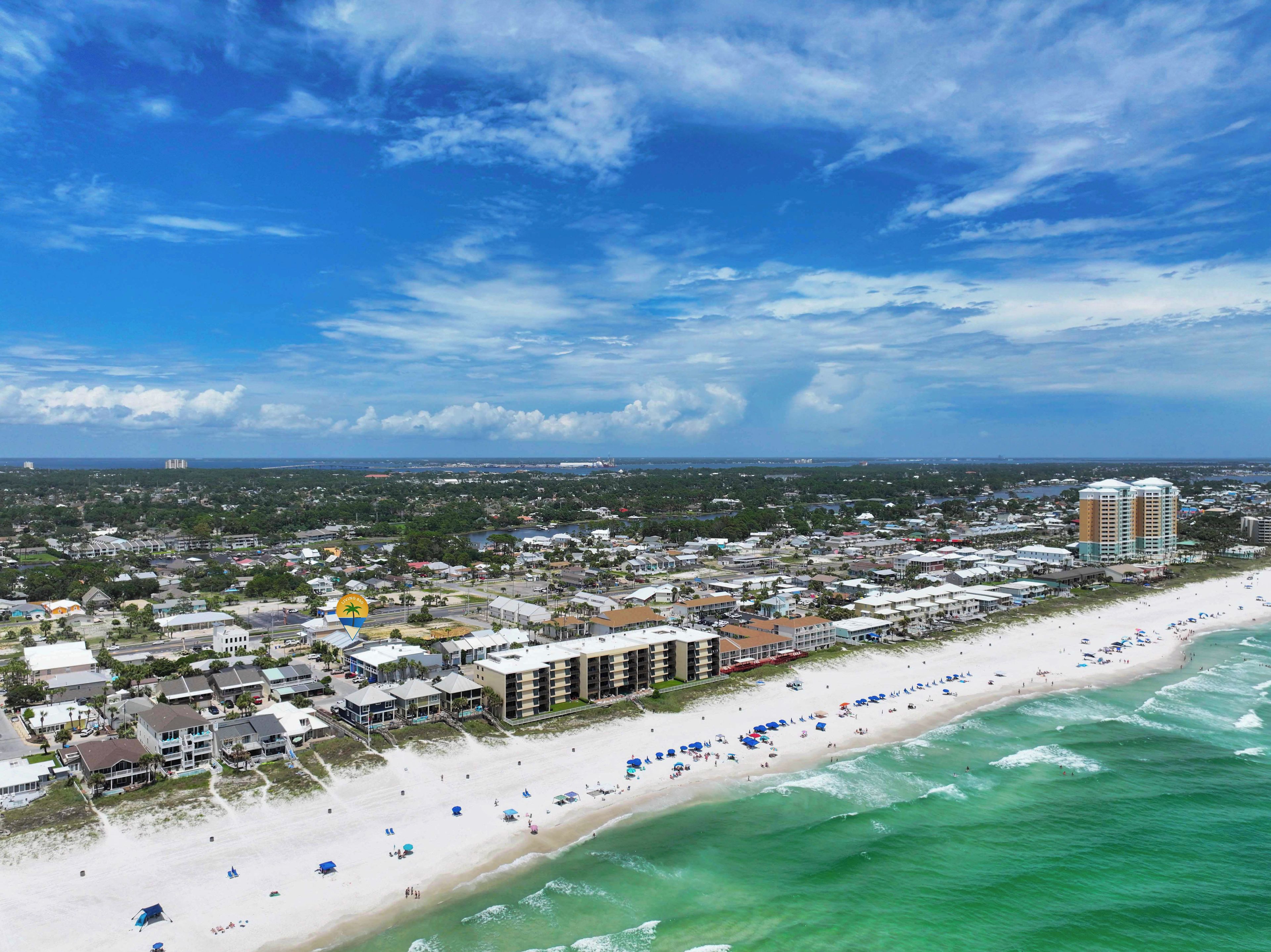 A coastal cityscape with a wide beach, beachfront hotels, and a clear sky.