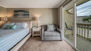 Une chambre à coucher comprenant un lit, des tables de chevet, une chaise et une grande fenêtre donnant sur un beau paysage.