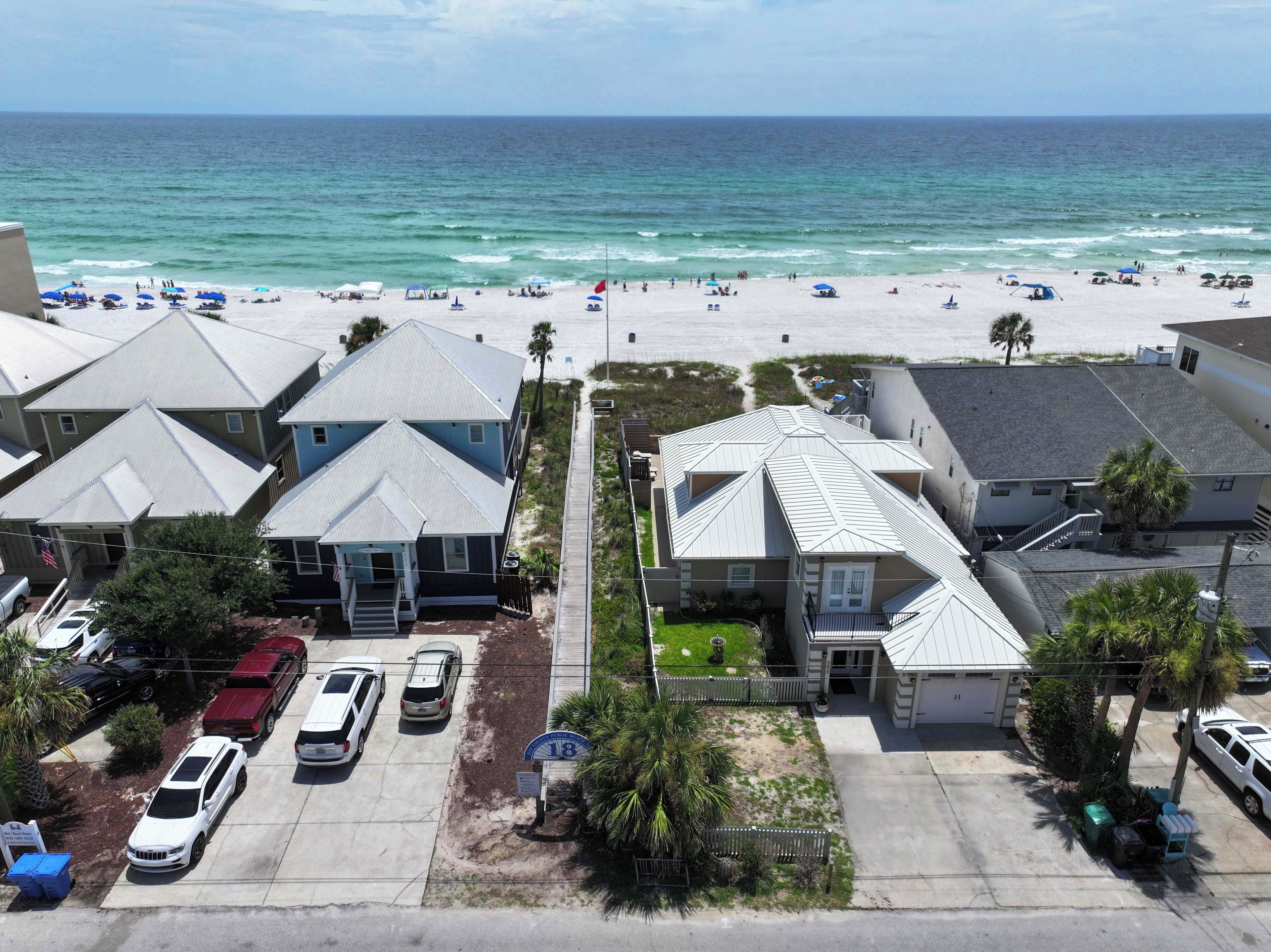 Une zone résidentielle côtière avec des maisons, une plage et des voitures garées.