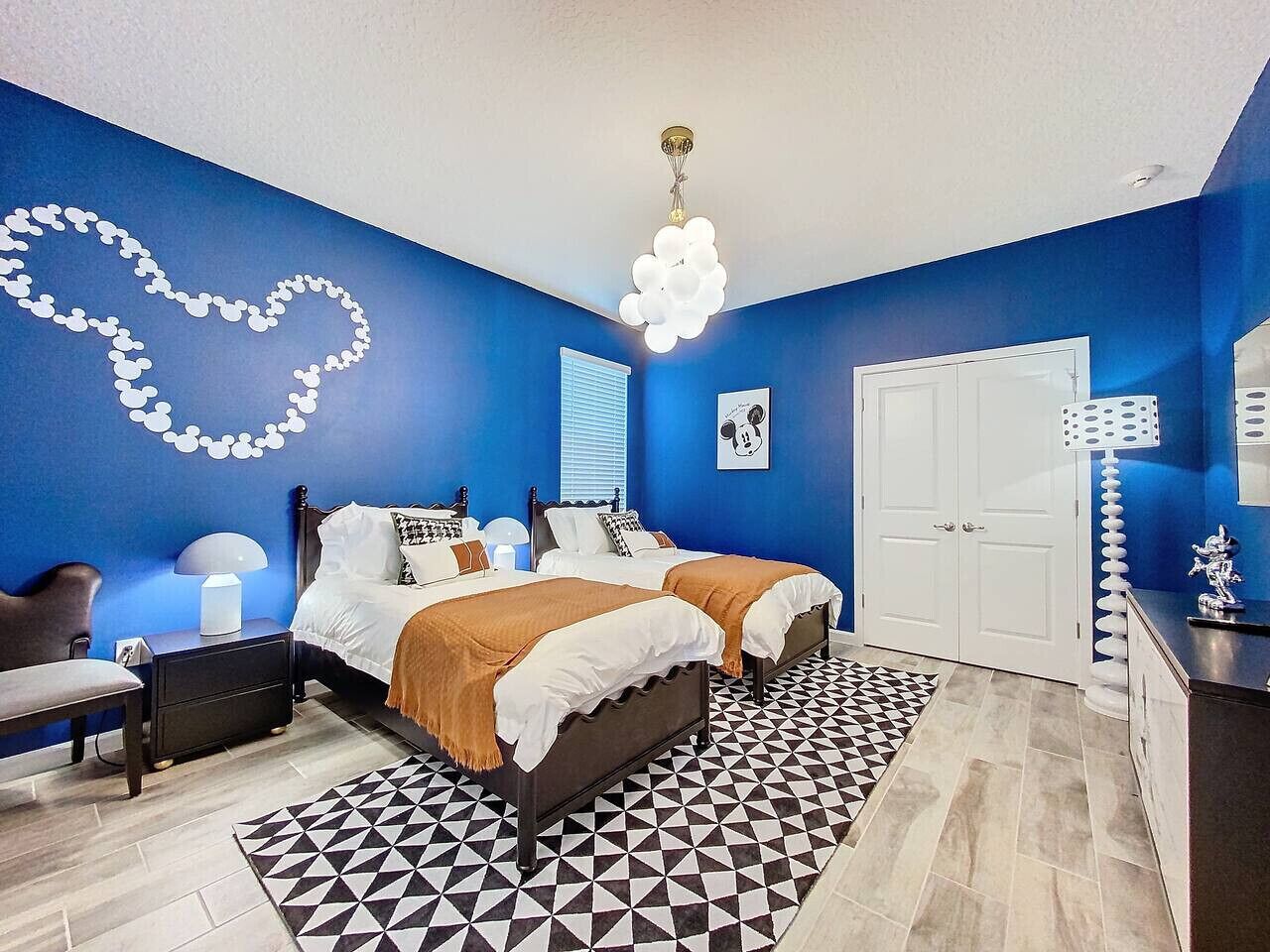 Une chambre avec deux lits, une table de chevet, une chaise, une commode et un tapis à motifs.