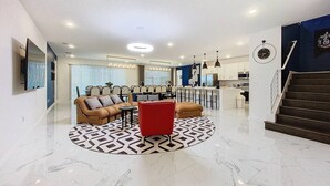 Un vaste espace de vie au design moderne, comprenant un coin salon central, une cuisine et un escalier menant à l’étage supérieur.