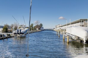 A marina with boats docked along a pier, a covered boat on the right, and a building with balconies on the right side. - 1 Mi to Beach: Bayside Townhome in Ocean City! (Ocean City)