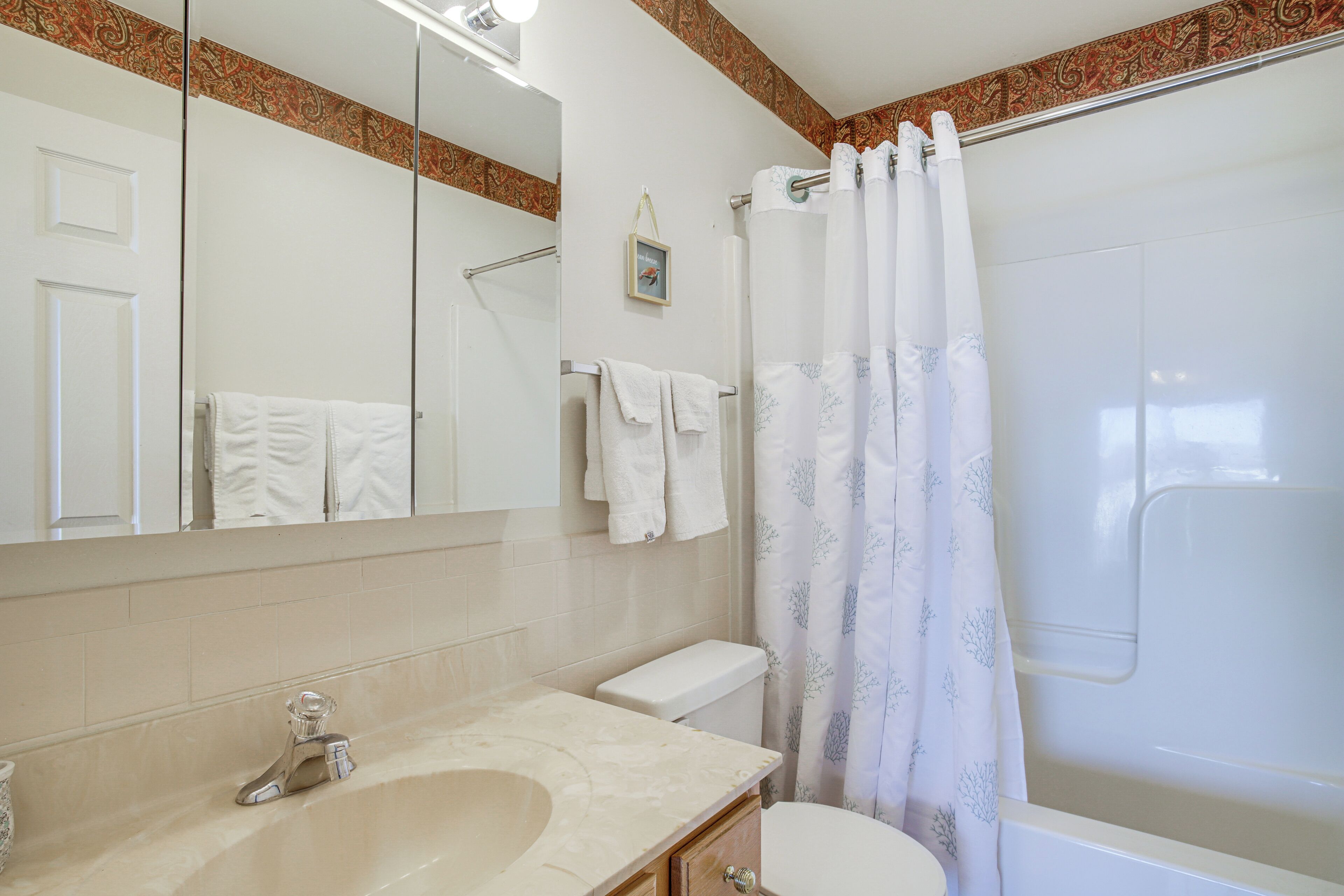 A bathroom with a sink, mirror, toilet, and shower curtain.