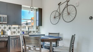Une cuisine moderne avec des meubles de couleur sombre, un four encastré et un coin repas comprenant une table ronde et des chaises.