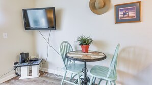 A small room with a TV mounted on the wall, a table with chairs, a potted plant, and a framed picture. - Walk to Beach: North Myrtle Beach Condo w/ Sunroom (North Myrtle Beach)