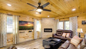 A cozy living room with a leather sofa, a coffee table, and a ceiling fan.