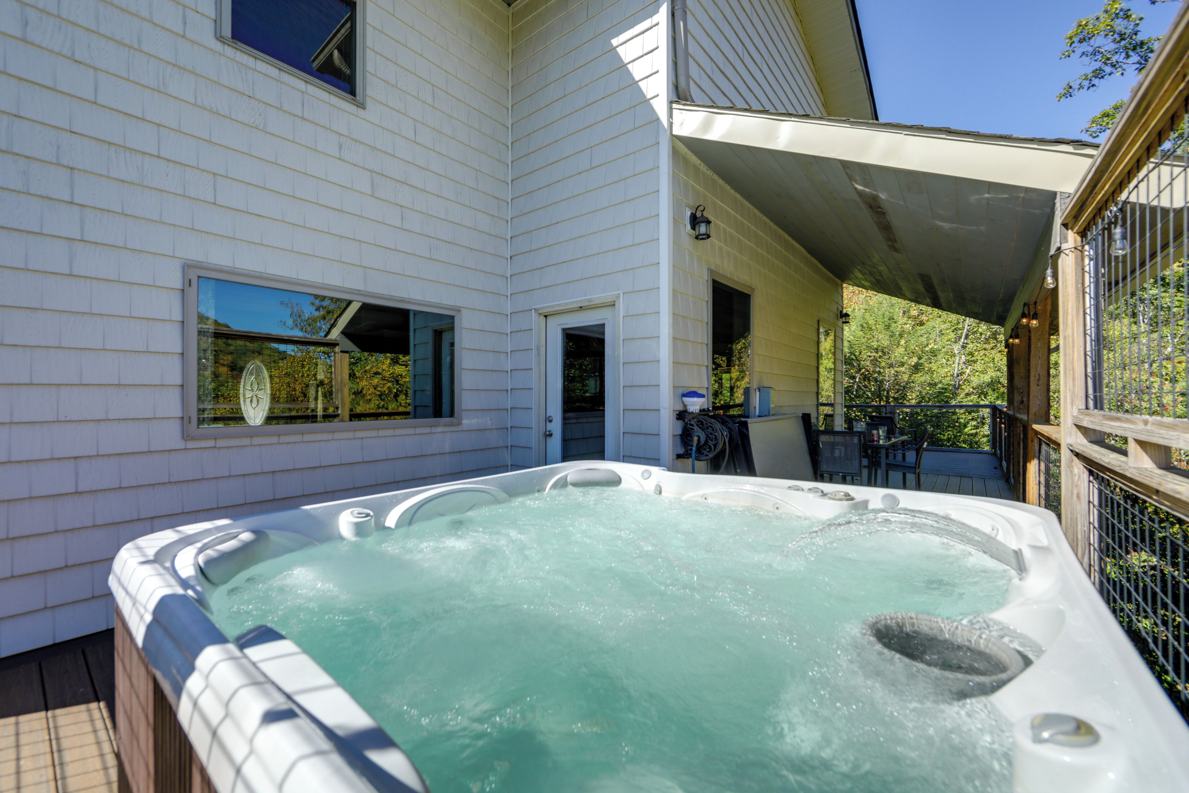 A hot tub on a wooden deck with a house in the background.