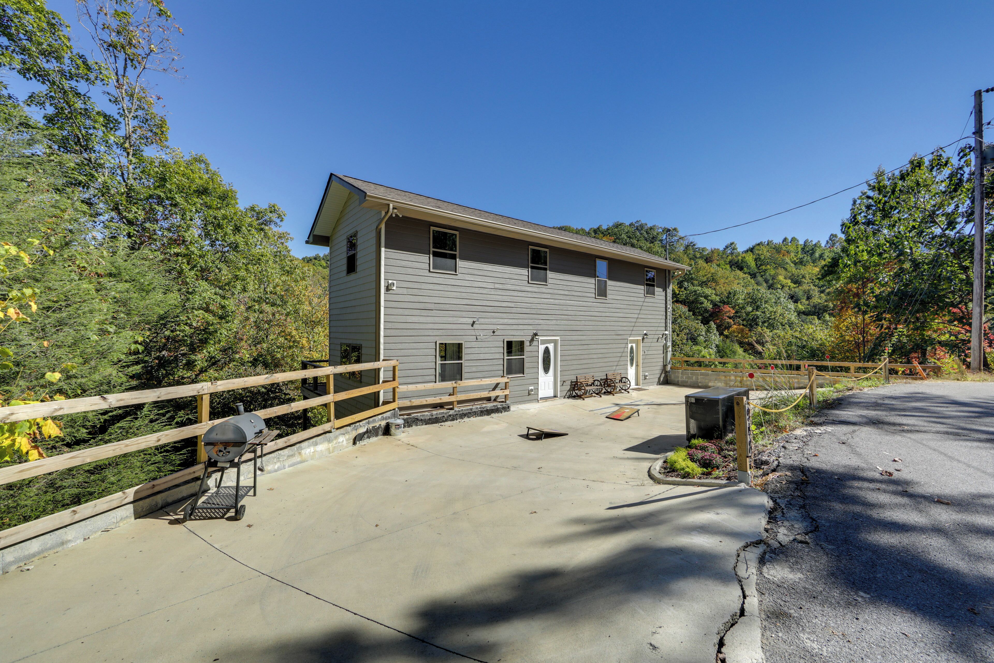 A two-story building with a wooden deck, a barbecue grill, and a small outdoor seating area.