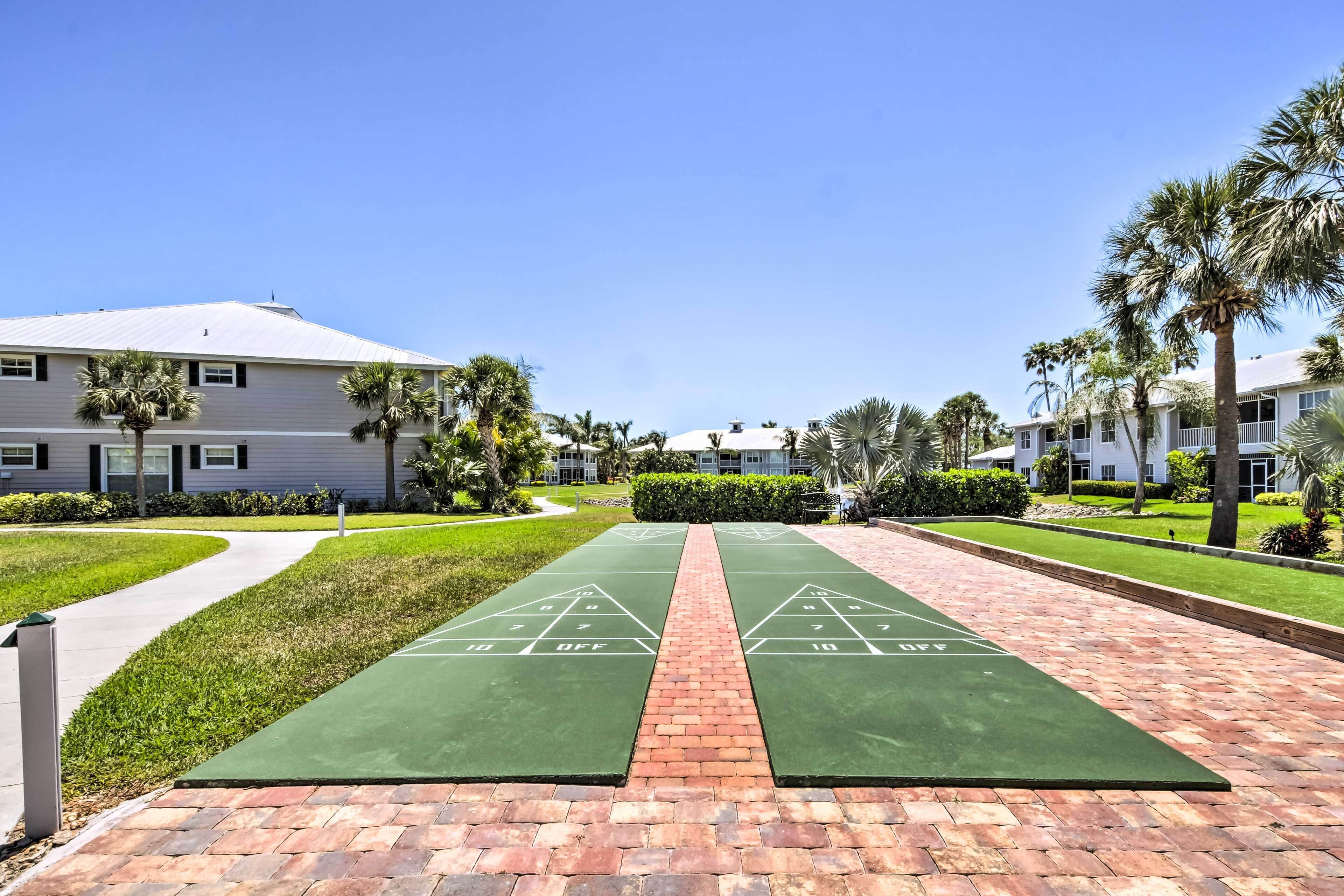 A courtyard with a shuffleboard court, surrounded by buildings and palm trees.