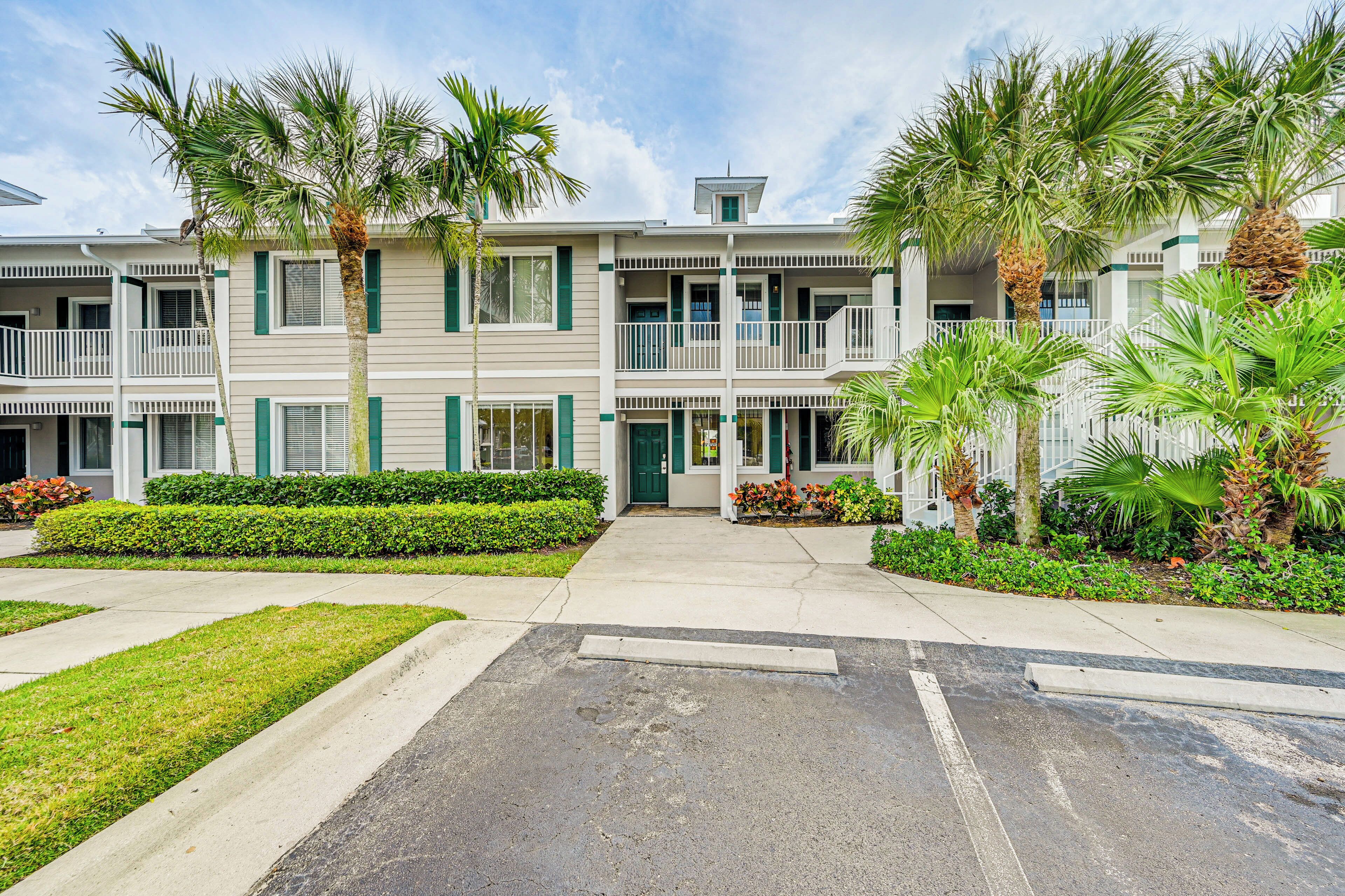 A two-story hotel with a central entrance, balconies, and palm trees.