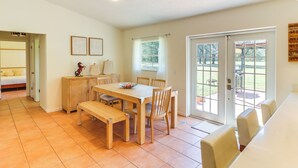 Un vaste espace dédié à la salle à manger, avec une table et des chaises en bois, un banc et une vue sur une terrasse extérieure, accessible par une porte vitrée.