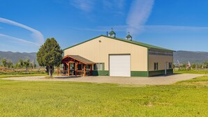 A large, single-story building with a green roof, a covered porch, and a garage door. - Thayne Retreat w/ Mountain Views - Near Trails! (Thayne)
