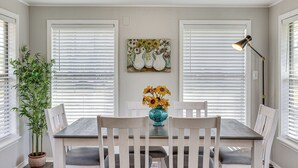 A dining area with a table, chairs, a vase with sunflowers, and a painting on the wall. - New Blaine Getaway - Walk to Lake Dardanelle! (New Blaine)