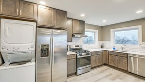 Una cocina moderna con electrodomésticos de acero inoxidable, armarios de madera y un amplio ventanal que proporciona luz natural.