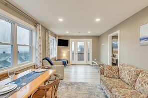 A spacious living room with a dining area, a sofa, and a television. - Newly Renovated Maine Retreat: Deck w/ Ocean View! (Lubec)