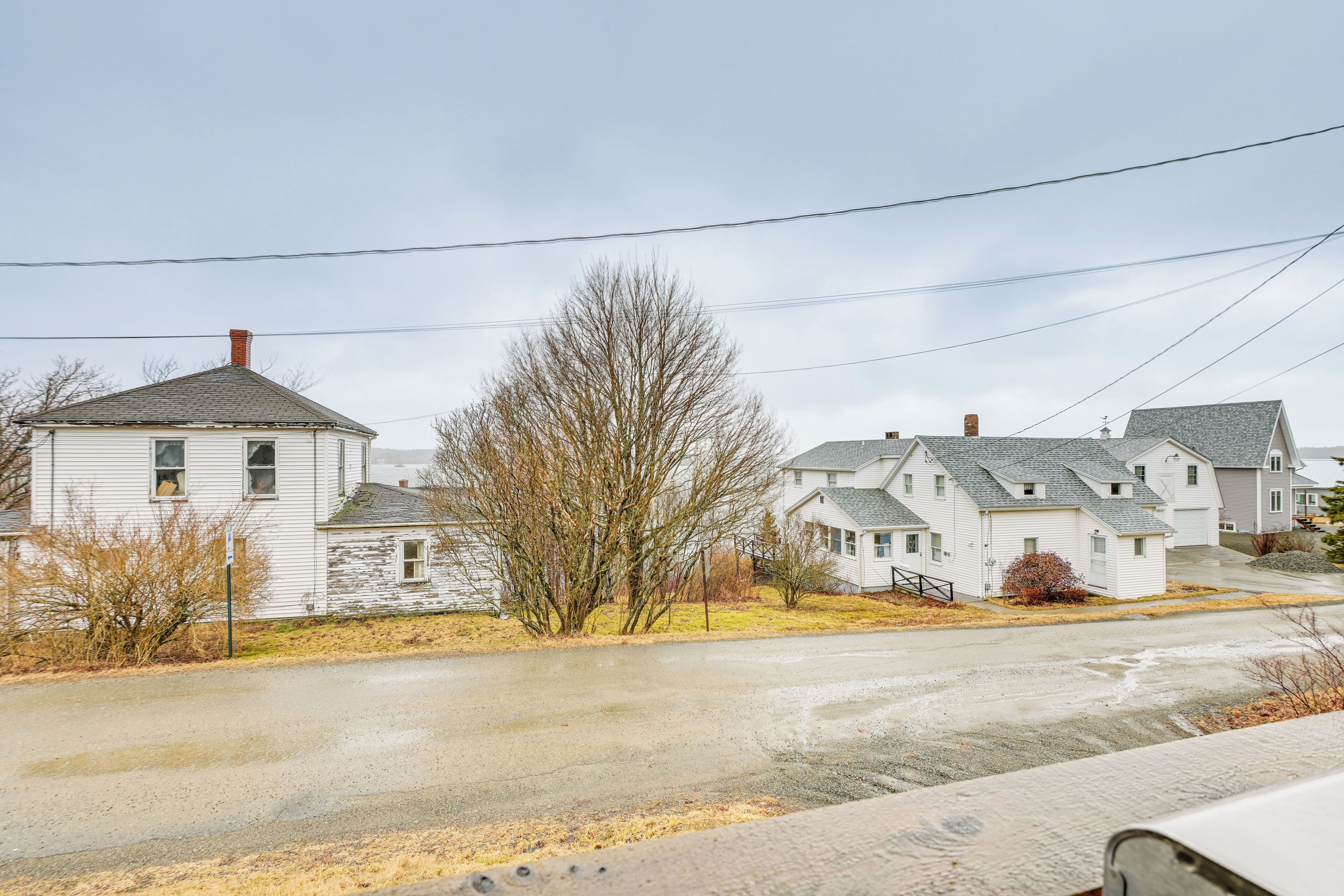 A residential street with houses, a clear sky, and power lines.