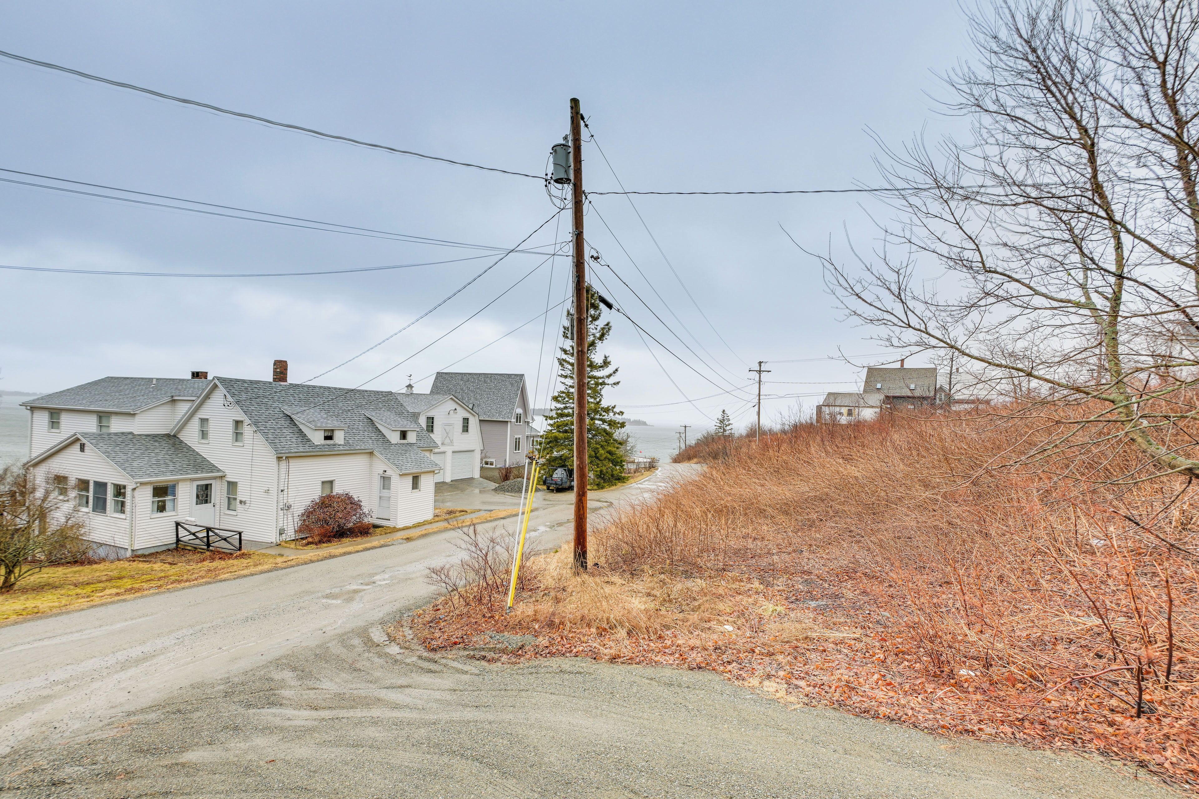 A residential street with houses, a dirt road, and utility poles.