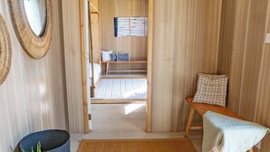 Una habitación con suelo de esterilla tatami, un banco de madera, una mesita y un espejo en la pared.