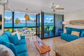 Una habitación con vista al océano, un ventilador de techo y una tabla de surf en la pared.