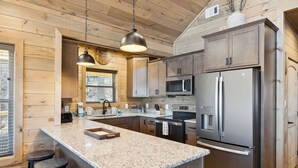 A modern kitchen with granite countertops, stainless steel appliances, and wooden cabinetry. - Tennessee Whiskey 3 Bedroom Cabin by RedAwning (Sevierville)