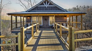 A wooden cabin with a metal roof, a covered walkway, and a star symbol on the front. - Tennessee Whiskey 3 Bedroom Cabin by RedAwning (Sevierville)