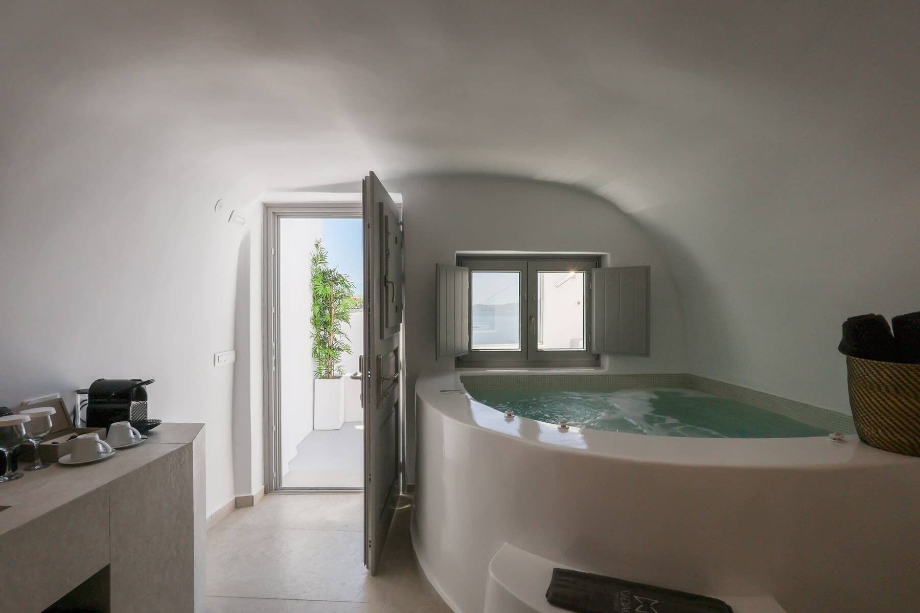 A modern bathroom with a freestanding bathtub, a window, and a plant.