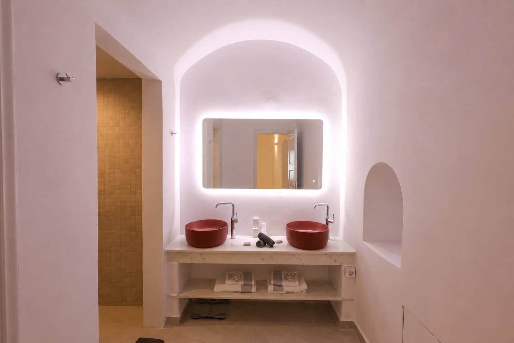 A bathroom with a white vanity, two red sinks, a mirror, and a towel rack.