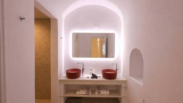 A bathroom with a white vanity, two red sinks, a mirror, and a towel rack.