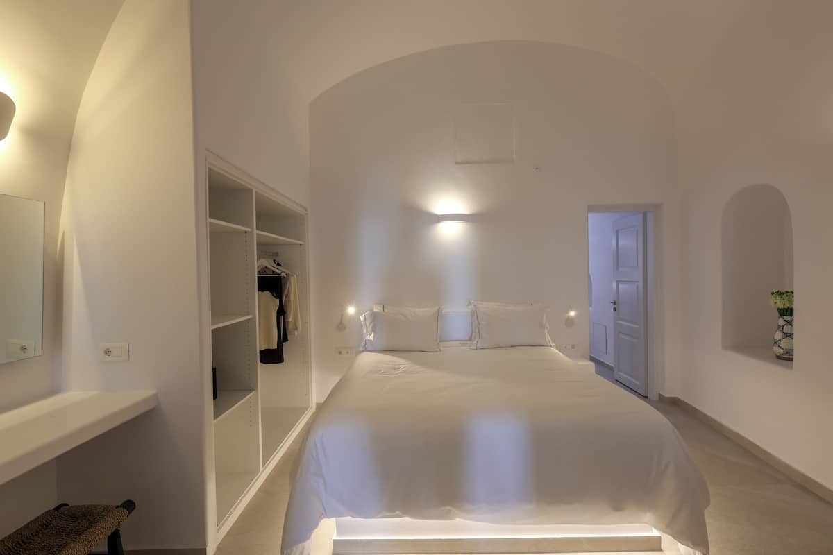 A bedroom with a large bed, a walk-in closet, and a mirror.