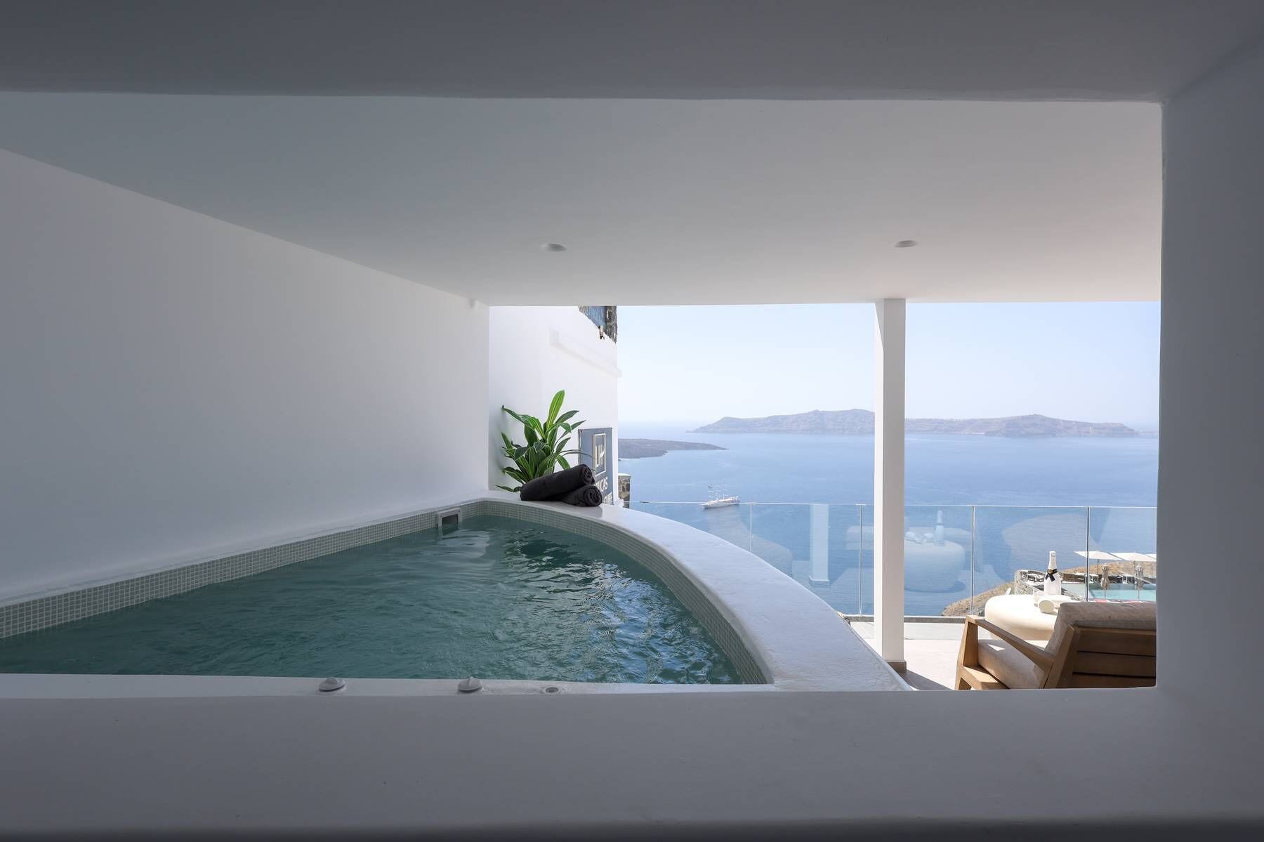 A modern indoor swimming pool with a view of the sea and distant islands.