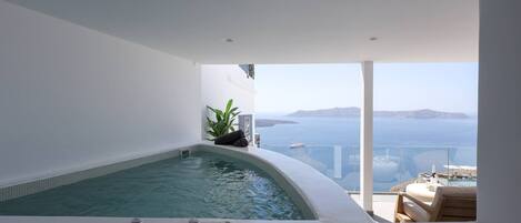 A modern indoor swimming pool with a view of the sea and distant islands.