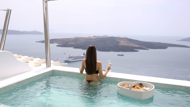 Una mujer en una piscina con vistas al mar y a las islas.