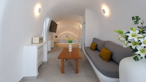 Un interior moderno con un sofá, una mesa de madera y un televisor montado en la pared.