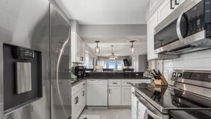 A modern kitchen with stainless steel appliances, white cabinetry, and pendant lighting. - New Renovated Beachfront Unit-Boardwalk 881-Gulf Shores-Signature Properties (Gulf Shores)