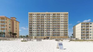 A beachfront hotel with multiple balconies, a sandy beach in front, and a signboard. - New Renovated Beachfront Unit-Boardwalk 881-Gulf Shores-Signature Properties (Gulf Shores)